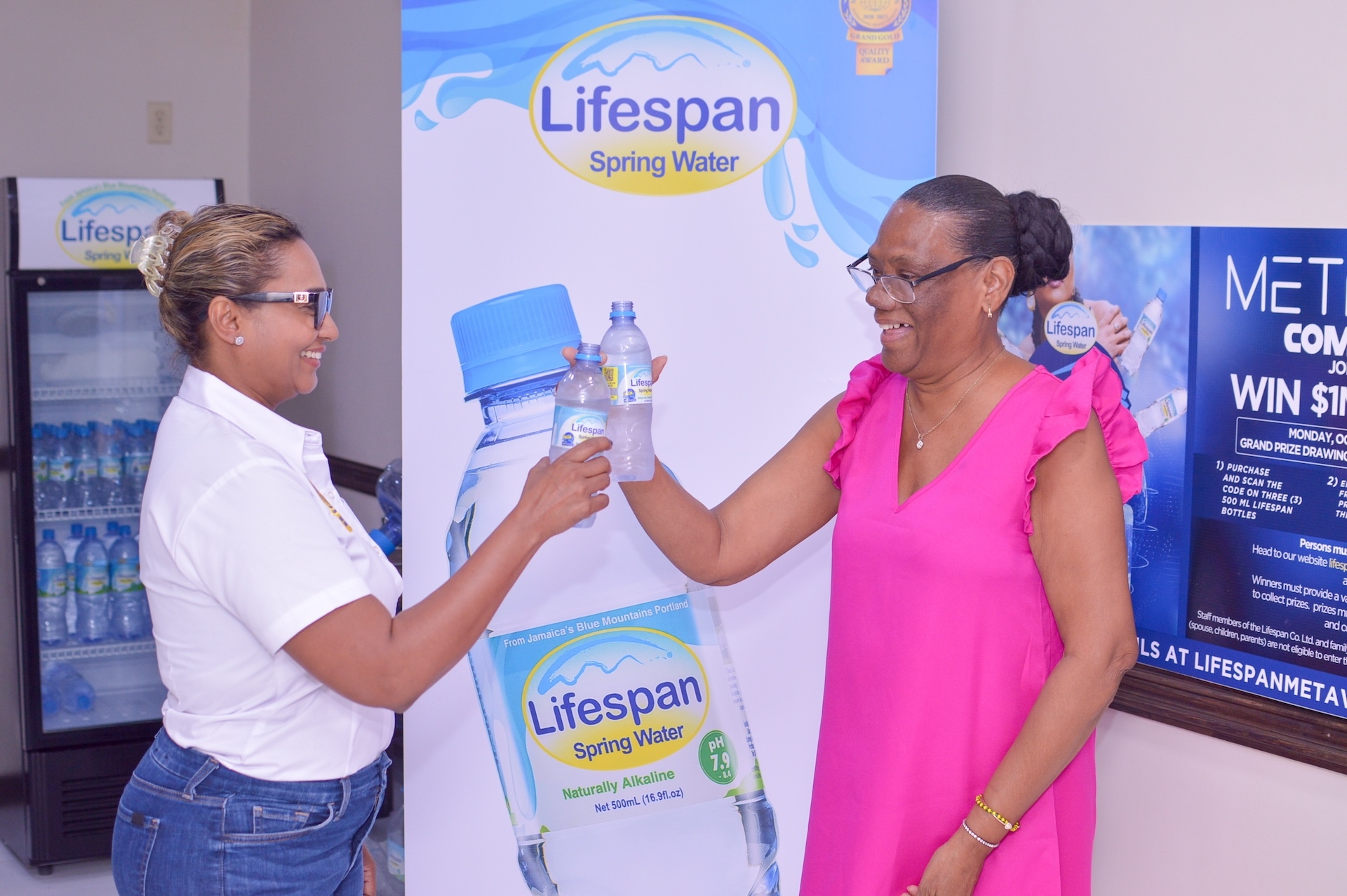 Lifespan’s CEO and Co-Founder Nayana Williams (l) and Dash and Win Winner Marcia Anderson enjoy bottles of Lifespan Spring Water at the company office recently